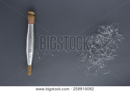 Silver Thread Pile Like Cloud And Spool Of Silver Thread. Reel Or Spool Of Silver Thread On Grey Bac