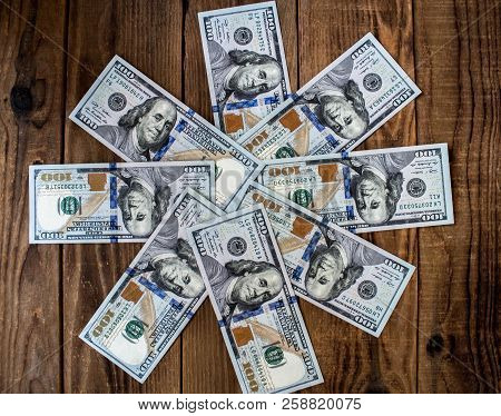 A Stack Of One Hundred Dollar Bils On Wooden Background