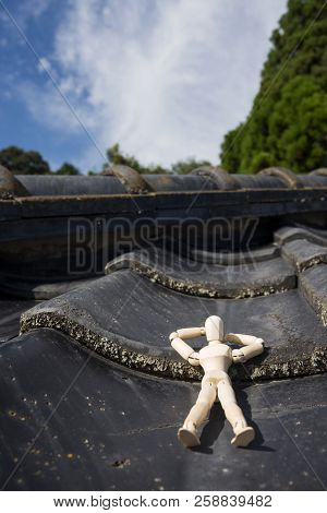 Wooden Doll Sleeping Face Up On A Asian Roof Tiles In Vertical Composition