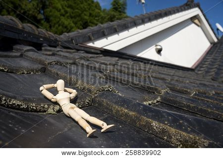 Wooden Doll Sleeping Face Up On A Asian Roof Tiles From An Oblique Direction