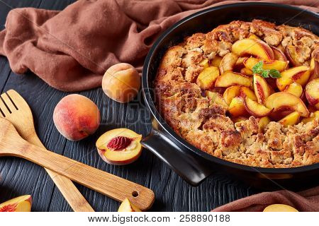 Close Up Of Fresh Organic Peaches And Delicious Peach Crumble Baked In A Black Ceramic Dish Seved On