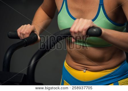 Strong Muscular Woman Training In Bike. High Intense Cardio Workout In The Gym.