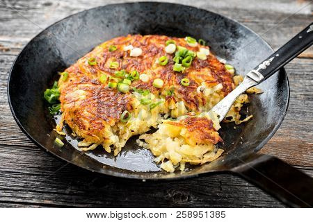 Traditional Swiss hash browns as side dish with leek as closeup in a frying pan 