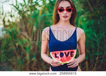 Beautiful Young Female In Swimsuit And Red Sunglassses Hold Slice Of Watermelon With Inscription Lov