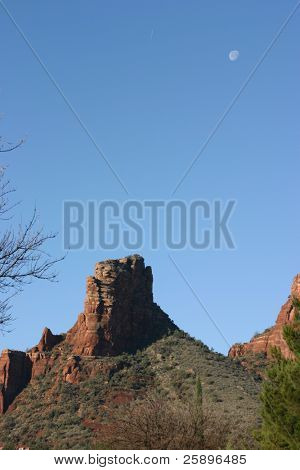 Luna si trova in alto nel cielo blu con uno di mountians bella roccia rossa di Sedona Arizona