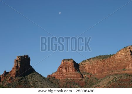 Luna si trova in alto nel cielo blu con uno di mountians bella roccia rossa di Sedona Arizona