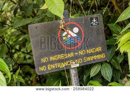 La Fortuna, Costa Rica. March 2018. A View Of A Wooden Sign Stating No Swimming And No Entance In Co