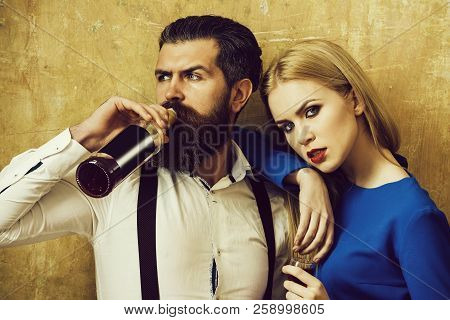 Hipster Drinking Wine From Bottle And Girl Holding Glass Of Liqueur. Pretty Woman With Blond Long Ha