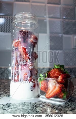 Fresh Strawberry Inside Of Glass Bottle. Falling Milk