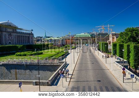 Sweden, Stockholm, May 31, 2018: Riksplan Green Grass Lawn, Bushes And Street With National Flags On