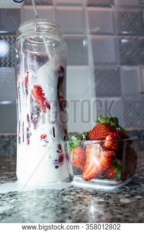 Fresh Strawberry Inside Of Glass Bottle. Falling Milk