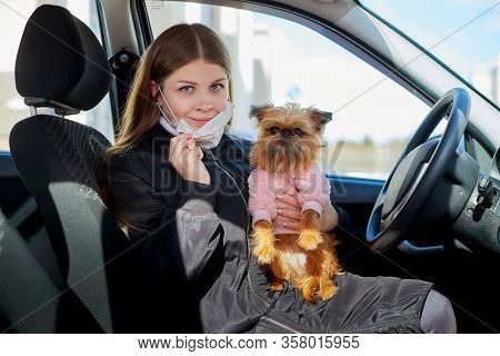 Girl In White Medical Gauze Mask In The Car With A Dog In Sunny Spring Day. Protection Against Disea
