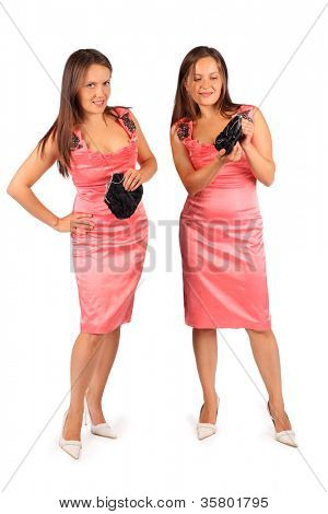 zwei gleiche Frauen tragen Rosa Abendkleid im Studio auf weißen Hintergrund. erste Frau schaut in die Kamera
