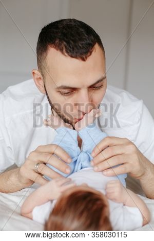 Happy Caucasian Father Holding Newborn Baby. Male Bearded Man Parent Hugging Kissing His Child Daugh