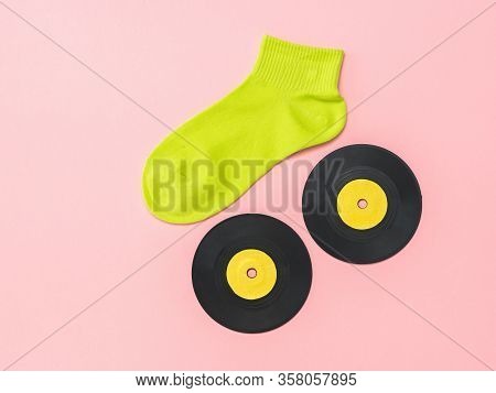 A Light Green Sports Sock And Vinyl Discs On A Pink Background. The Concept Of Music And Sports. Fla