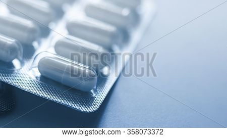 One Blister Of Pills Closeup. Oval Long Shape Remedies. Blue Tone, Sun Fleck. Background Or Texture 