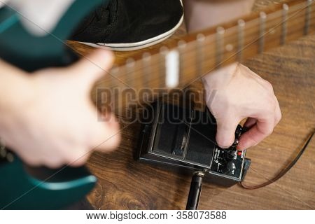 Man With Musical Instrument Setting Up Guitar Audio Stomp Box Effects And Cables In Music Studio