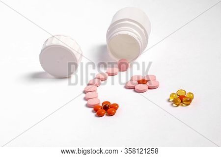 White plastic bottle with medicines and vitamines. tematic health. rose, yellow and red medicines.