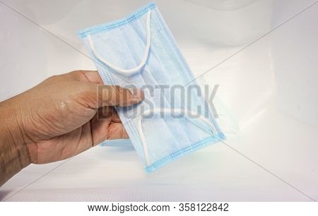 Closeup Hand Disposable Face Mask With Earloop. Protective Mask On Infected Trash Protecting The Res