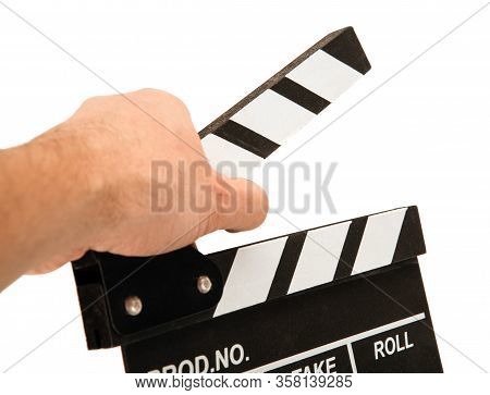 Black Movie Clapper With White Inscriptions In The Hand On A White Table Closeup