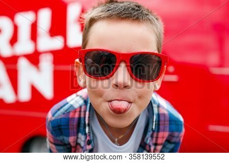 Naughty Boy Sticks Out Tongue Outdoors In City