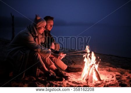 Winter Picnic On Baech With Bonfire. Love Story On Winter Foggy Sand Beach. Fry Marshmallows At The 