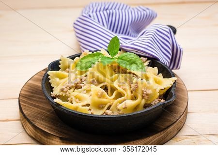 Ready-to-eat Pasta Navy With Minced Meat And Basil Leaves In A Iron Frying Pan On A Wooden Table. Ru