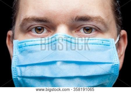 Male Portrait A Close Up Of A Face With A Serious Expression In A Blue Medical Mask Isolated On A Bl