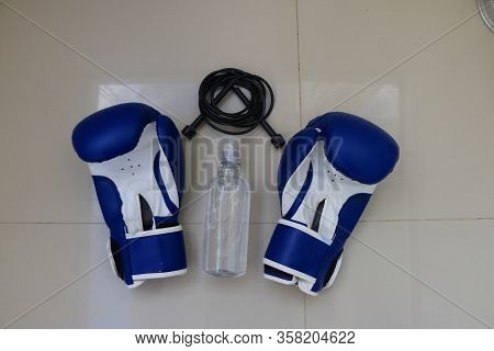 Exercise At Home To Avoid The Coronavirus. A Pair Of Boxing Gloves, A Skipping Rope And Alcohol Gel
