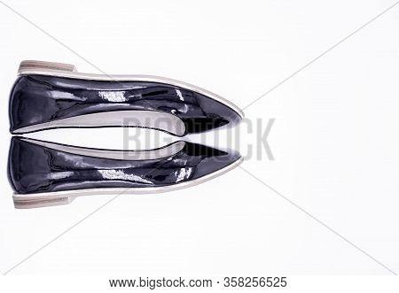 A Pair Of Black Patent Leather Shoes With A Low Heel And A Gold Stripe Along The Sole On A White Bac