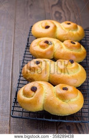 Swedish And Scandinavian Christmas Saffron Buns Lussekatter On A Cooling Tray, Brown Wooden Backgrou