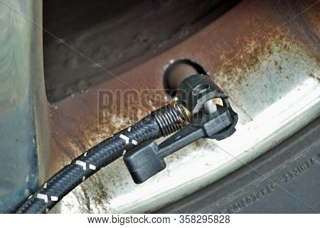 Close Up Of A Portable Air Compressor Connected To The Valve Stem Of A Car Tire