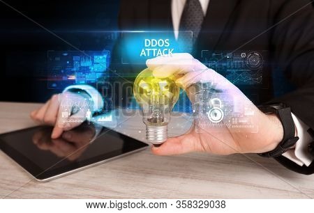 Businessman holding lightbulb with DDOS ATTACK inscription, online security idea concept