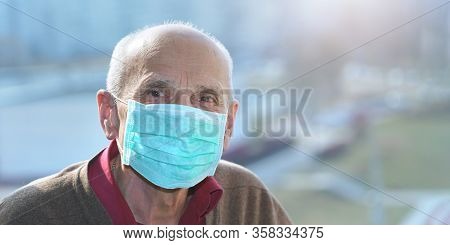 Old Man In Protective Face Mask Anti Virus Looks In Camera Window Background