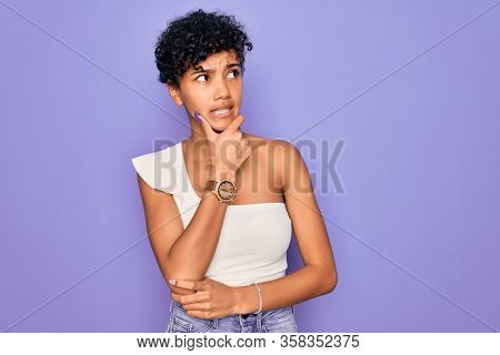 Young beautiful african american afro woman wearing casual t-shirt over purple background Thinking worried about a question, concerned and nervous with hand on chin