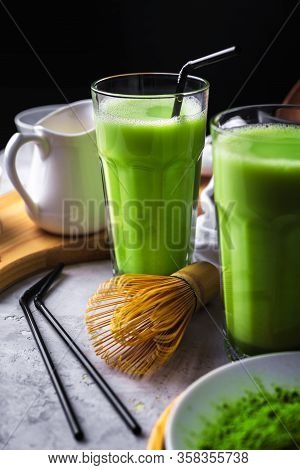 Matcha Green Tea Powder Latte With Milk In Two High Glass On Stone Table, Black Straw, Wooden Plate 