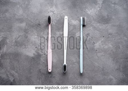 Flat Lay Composition Of Multi-colored Toothbrushes With Black Bristles On A Gray Background.