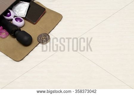 An Open Female Bag With Which A Vibrator, Kegel Balls, A Condom, A Phone And Other Toys For Adults G