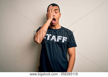 Young handsome african american worker man wearing staff uniform over white background Yawning tired covering half face, eye and mouth with hand. Face hurts in pain.