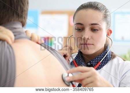 Woman Therapist In Clinic Listens To Lungs Man. Patient Is Referred To General Practitioner Or Gener