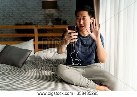 Portrait Of Happy 30s Aged Asian Man In Casual Clothing Making Facetime Video Calling With Smartphon