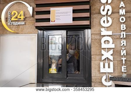Kiev, Ukraine, 27 March 2020, Man In Facial Protective Mask Gives Fastfood Hamburgers Thru Window At