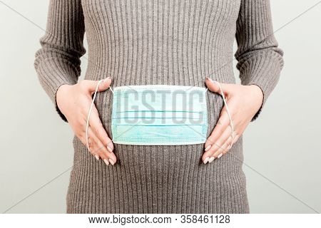 Medical Mask On The Belly Of A Pregnant Girl. Hild Protection. Concept Of Coronavirus, Covid-19, Qua