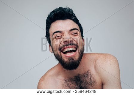 Young Man Isolated Over Background. Laugh Of Madness. Naked Chest. Sit Alone In Room. Mental Disorde
