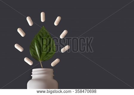 White Jar With Pills And A Green Leaf On A Gray Background