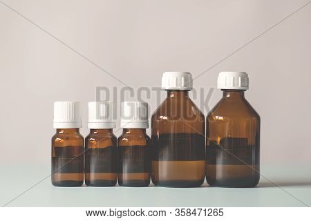 Bottles Of Medicine Lined Up On A White Background. Chemical Experiments, Vaccines, Blood Tests