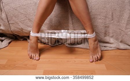 Legs And Feet Of Unrecognizable Young Woman With White Thong Panties Around Her Ankles On Bedroom Fl