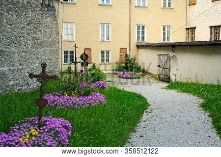 Pathway Inside The Old Nonnberg Abbey In Salzburg, Austria, With Flowers And Grave Markers