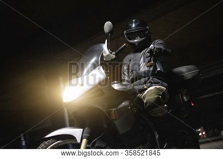 Motor Biker On A Motorcycle Is Showing At Screen By His Index Finger.