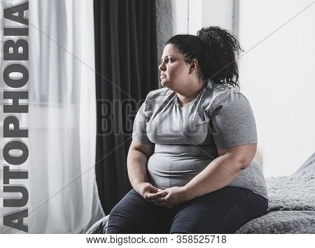 Depressed Overweight Woman Sitting Alone On Bed At Home. Autophobia